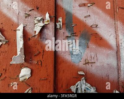 Öffentliches Holzbrett, rotbraun gestrichen, mit kleinen Papierfetzen und Heftklammern Stockfoto