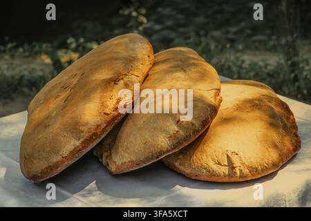 Drei traditionelle handgemachte Brotsorten mit goldener Kruste, frisch gebacken, ruhen auf weißem Tuch. Abruzzen, Italien, Europa Stockfoto