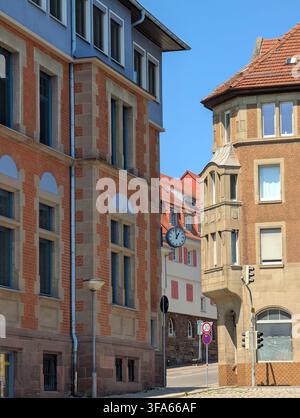 Eine ruhige urbane Straßenszene mit historischen Gebäuden aus leuchtend rotem Backstein und blauem Himmel, die eine visuell beeindruckende und friedliche Atmosphäre schaffen. Stockfoto