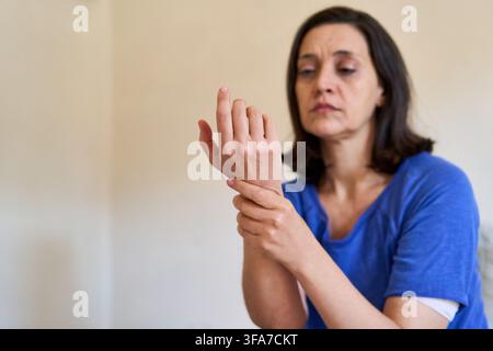 Handgelenkschmerzen und Verletzung, Frau hält ihr schmerzendes Handgelenk, Karpaletunnelsyndrom und Gelenkbeschwerden. Erwachsene Frau, die ein Gesundheitsproblem erlebt, Physi Stockfoto