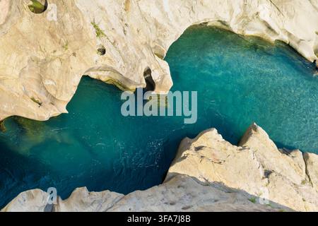 Türbliches Bergwasser fließt durch glatte helle Kalksteinformationen in den Dolomiten, Italien, und bildet natürliche Pools und kleine Felsbögen. Stockfoto