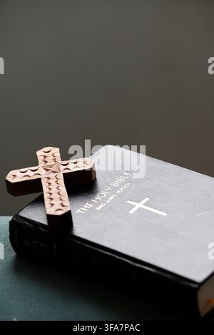 Handgeschnitztes dekoratives Holzkreuz auf schwarzem Lederbezug der Heiligen Bibel. Stockfoto
