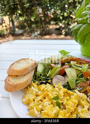 Gesundes Frühstück im Freien: Rührei, Avocado, Rucola, Toast. Konzept von Wellness, ausgewogener Ernährung, Fitness-Lebensstil und lebendiger Sommerfrische Stockfoto