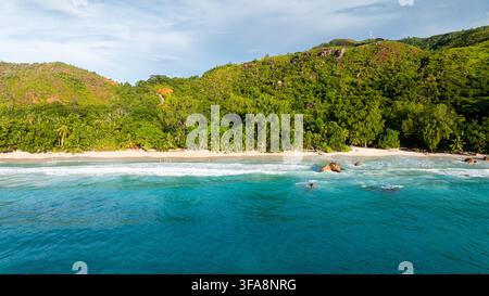 Eine ruhige Bucht mit türkisfarbenem Wasser ist von üppigen grünen Bergen umgeben. Anse Lazio, Seychellen. Stockfoto