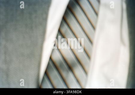 Nahaufnahme einer abstrakten Aufnahme von diagonal gerippten architektonischen oder strukturellen Elementen in gedämpften Silber- und Beigetönen, mit weicher Bokeh-Unschärfe, die eine träumerische Atmosphäre erzeugt Stockfoto