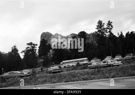 Schwarz-Weiß-Vintage-Foto des Mount-Rushmore-Nationaldenkmals in South Dakota, mit einem Parkplatz voller klassischer Autos der 1960er Jahre und einer Stockfoto