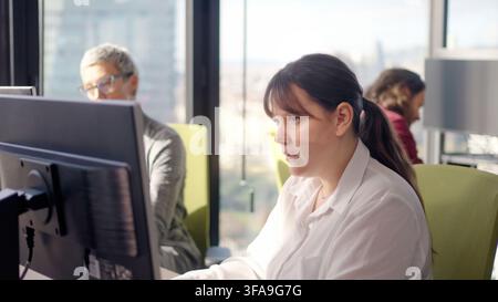 Konzentrierte Geschäftsfrau arbeitet am Computer in einem modernen Großraumbüro Stockfoto