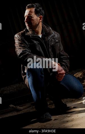 Ein stilvoller, dunkelhaariger, schlanker, 40-jähriger weißer Mann. Er trägt blaue Jeans und einen braunen Pelzmantel. Stockfoto
