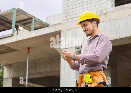 Bautechnologie und digitales Projektmanagement, lächelnder Ingenieur verwendet ein Tablet auf einer Baustelle Stockfoto