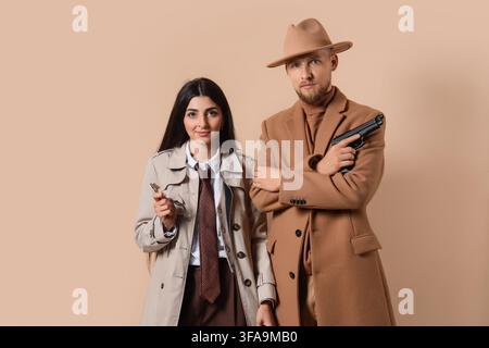 Detektivagentur und Privatermittlungskonzept, Mann und Frau in Trenchcoats mit Waffe und Lupe Stockfoto
