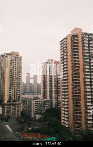 Dichte städtische Landschaft mit hoch aufragenden Wohnhochhäusern und Wolkenkratzern unter einem dunstigen Himmel, Chongqing, China. Stockfoto
