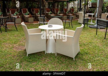 Runder Gartentisch mit Rattanstühlen auf grünem Kunstgras in einer Open-Air-Spa- oder Massagestätte, Entspannungs-Lounge-Konzept Stockfoto