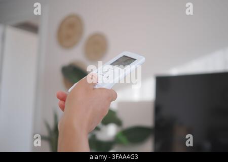 Hält eine Fernbedienung in einer Wohnzimmersituation Stockfoto