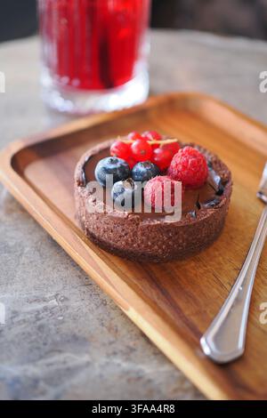 Schokoladentarte mit Beeren auf Holzplatte Stockfoto