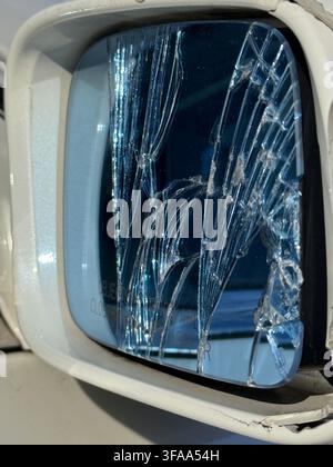Nahaufnahme eines zerbrochenen Autospiegel, mit gesprungenem Glas und verzerrten Reflexionen Stockfoto
