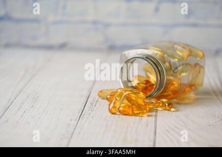 Verschüttete Flasche mit Fischölkapseln auf Holzoberfläche Stockfoto