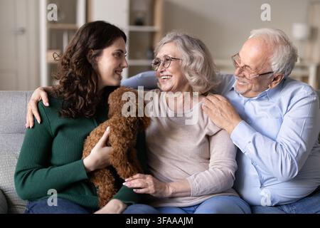 Tochter sitzt mit den betagten Eltern und dem Familienhund auf dem Sofa Stockfoto