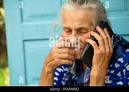 Eine ältere Frau telefoniert und fühlt sich während eines Telefonats gestresst Stockfoto