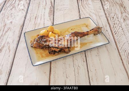 Gebratenes Lammhals mit gekochten Kartoffeln und Knoblauchsauce, serviert auf einem rechteckigen weißen Teller mit blauem Rand. Stockfoto