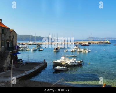 Kleine Motorboote, Yachten und Fischerboote, die an einem ruhigen mediterranean Hafen an einem hellen Sonnentag vor Anker liegen, mit fernen Hügeln am Horizont. Stockfoto
