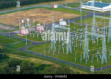 Luftaufnahme eines Umspannwerks, das Hochspannungsstrom verteilt und transformiert, mit Metalltürmen, Transformatoren und gepflasterten Wegen Stockfoto