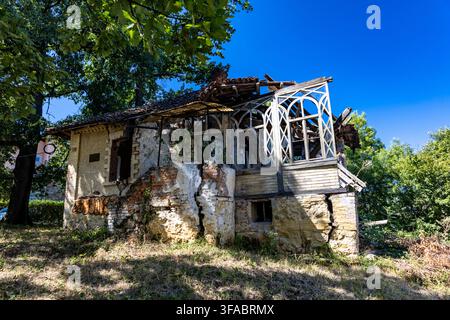 Verlassenes und stark verfallenes altes Haus in Serbien mit eingestürztem Dach, einst eine luxuriöse kleine Villa, jetzt umgeben von überwucherter Vegetation Stockfoto
