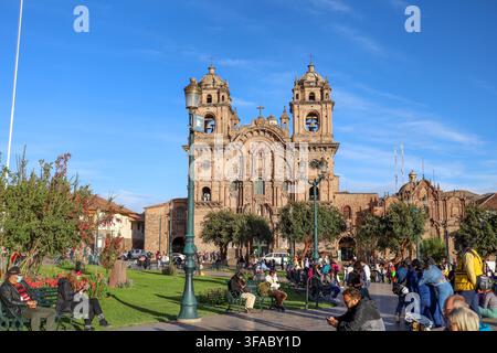 Cusco, Peru - 17. Mai 2022: Blick auf die Kirche der Gesellschaft Jesu im Plaza de Armas mit ihrer kunstvollen kolonialen Fassade, zwei Glockentürmen und Menschen Stockfoto