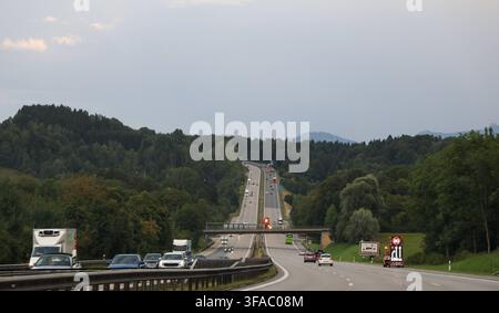 Bayern, Deutschland, Europa: Verkehr auf der Bundesautobahn A9 in einer bewaldeten Landschaft. Pkw und Lkw befahren beide Fahrtrichtungen, während eine mobile Verkehrsabsicherung mit elektronischer Wechselverkehrsanzeige auf bevorstehende Fahrstreifenregelungen und eine Geschwindigkeitsbegrenzung hinweist. Weitwinkelaufnahme einer wichtigen Nord-Süd-Verkehrsachse unter bewölktem Himmel. *** Bayern, Deutschland, Europa: Verkehr auf der Bundesautobahn A9 in einer bewaldeten Landschaft. Pkw und Lkw befahren beide Fahrtrichtungen, während eine mobile Verkehrsabsicherung mit elektronischer Wechselverkehrsanzeige auf bevorstehende Fahrstreifenregelungen und eine Geschwindigkeitsbegrenzung hinweist. Weitwinkelaufnahme einer wichtigen Nord-Süd-Verkehrsachse unter bewölktem Himmel. Stockfoto