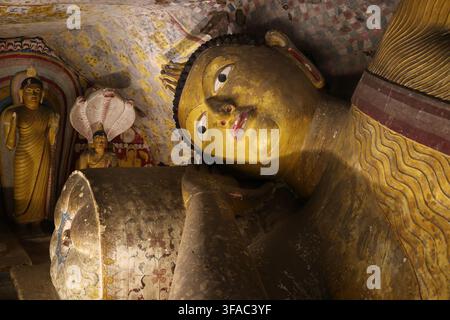 Nahaufnahme eines liegenden Buddha-Kopfes auf einem Kissen in einem der historischen Dambulla-Höhlentempel, die unter einem massiven Felsvorsprung in Sri Lanka erbaut wurden Stockfoto