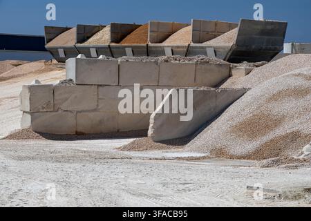 Massive Haufen von Kies und Sand werden in großen Betonbehältern und auf dem Boden in einer Materialaufbereitungsanlage gelagert Stockfoto