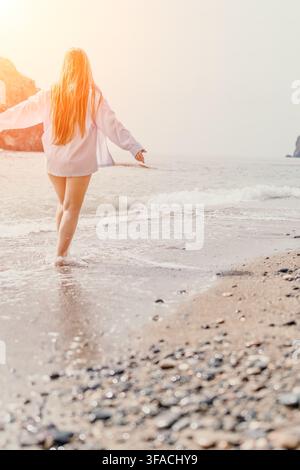 Frau am Strand, junge Frau mit langen blonden Haaren geht bei Sonnenuntergang entlang der sandigen Küste mit Kopierraum Stockfoto