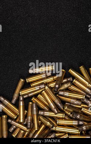 Verstreute leere Messingpatronenhülsen, die auf dunklem, strukturiertem Schaumstoffhintergrund liegen. Stockfoto
