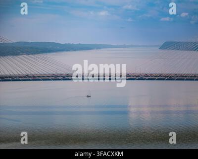 Luftbild der Governor Mario M. Cuomo Bridge, die den Hudson überquert, mit einem kleinen Segelboot darunter und üppigen grünen Hügeln in Tarrytown, New York, U Stockfoto