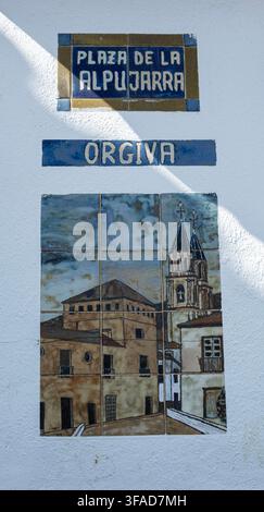 Dekoratives Keramikschild und Stadtbild, das Órgiva auf der Plaza de la Alpujarra in Órgiva, Las Alpujarras, Provinz Granada, Andalusien, Spanien zeigt. Stockfoto