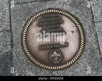 Dublin, Irland – 22. Mai 2026: Bronzene kreisförmige Pflasterplakette auf der Dame Street in Dublin, die das erste Pfadfinder-Treffen der Wolf Patrol in Irland gedenkt Stockfoto