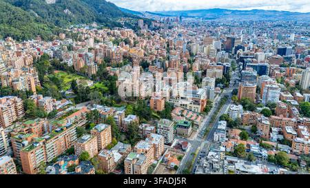 Ein weitläufiger Blick auf die lebendige Stadtlandschaft von Bogotá, der farbenfrohe Gebäude und üppige Grünflächen unter einem teilweise bewölkten Himmel zeigt. Stockfoto