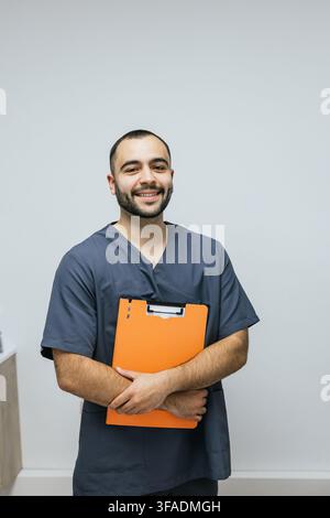 Lächelnde Gesundheitsfachkraft hält ein orangefarbenes Klemmbrett Stockfoto