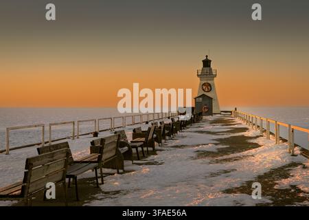 Historisches Leuchtturm von Port Dover und Holzbanken, die bei Sonnenaufgang im Schnee liegen, Lake Erie, Ontario, Kanada. Stockfoto