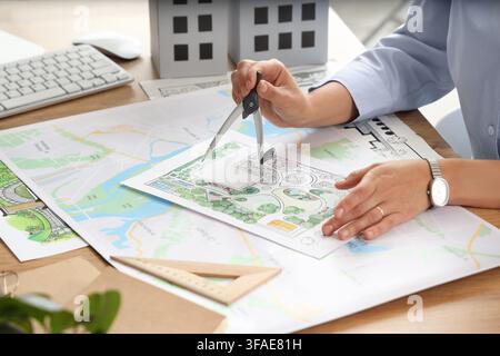 Landschaftsarchitektur und Stadtplanung, Designer arbeitet an einem Gartenprojekt mit Kompass und Karte auf einem Holztisch Stockfoto