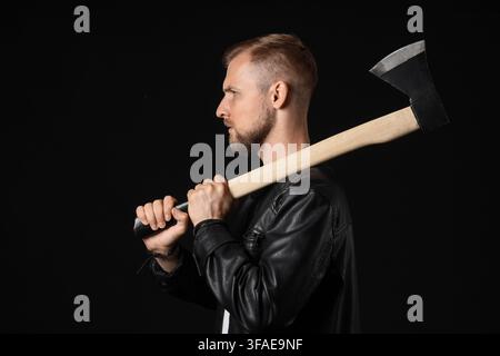 Aggression und Gefahr Konzept Mann mit einer Axt auf der Schulter Gewalt und Bedrohung isoliert auf einem dunklen Hintergrund Stockfoto