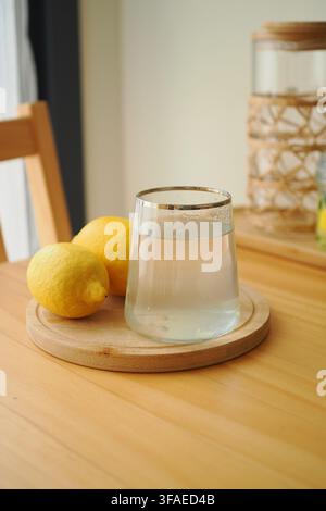 Zitrone und Wasser auf einem Holztisch in einem hellen Raum Stockfoto