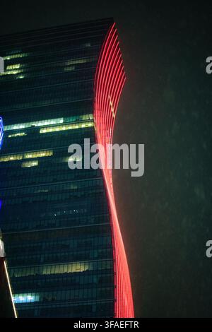 MANDALUYONG CITY, PHILIPPINEN - 1. JANUAR 2026: Niedrige Blickwinkelaufnahme des SM Mega Tower mit vertikalen roten LED-Lichtern an einem regnerischen Abend im Ortigas Center. Stockfoto