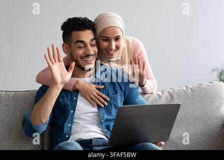 Mann und Frau aus dem Nahen Osten winken am Laptop-Bildschirm Stockfoto