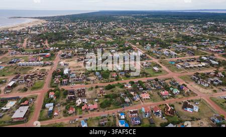 Eine weitläufige Luftaufnahme, die das lebendige Wohngebiet von Punta del Diablo, Uruguay, einfängt. Das Bild zeigt farbenfrohe Häuser, sich windende Straßen, Stockfoto