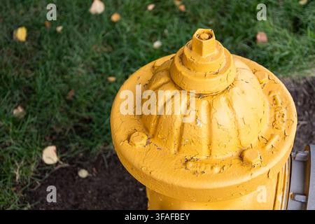 Nahaufnahme der Spitze eines gelben Feuerhydranten, der abgenutzte, rissige und abblätternde Farbe zeigt. Stockfoto