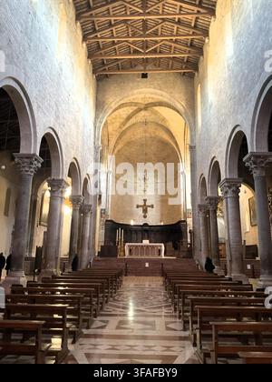 Weite Ansicht des Hauptschiffs, das zum Hauptaltar führt, und hängendes Holzkreuz in der Kathedrale Duomo di Todi, Umbrien, Italien. Stockfoto