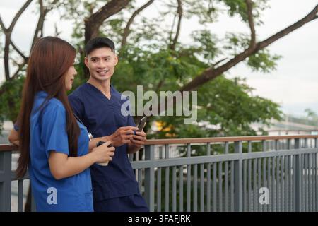 Asiatisches medizinisches Personal, das Smartphone verwendet und während der Pause im Freien spricht Stockfoto