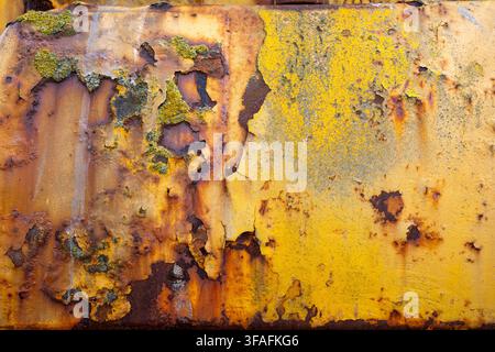 Nahaufnahme von verrosteter, abblätternder gelber Farbe auf einem alten Traktor, der zum Starten von Booten an der Aldeburgh-Bucht in Suffolk verwendet wird, seine verwitterte Metalloberfläche ist mit Pa bedeckt Stockfoto