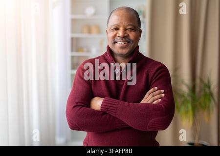 Selbstbewusster reifer schwarzer Mann steht zu Hause mit verschränkten Armen Stockfoto