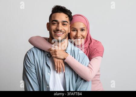 Portrait Des Muslimischen Paares Umarmt Über Grauem Hintergrund Und Lächelnd An Der Kamera Stockfoto